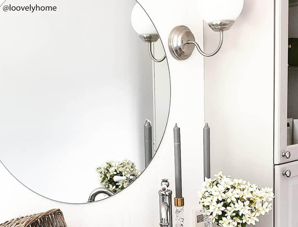 Miroir rond, fleurs et bougies dans salle de bain